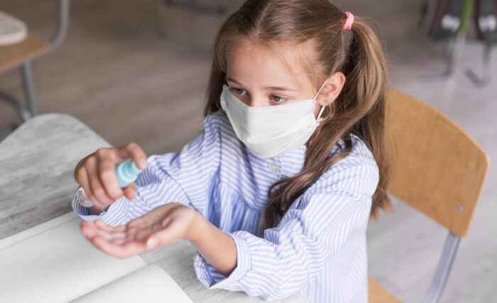 high-angle-kid-disinfecting-her-hands